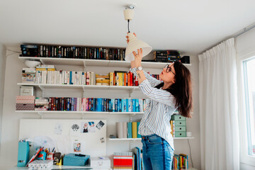 Woman changing bulb in house, Sweden