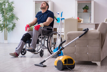 Fototapeta na wymiar Young leg injured contractor in wheel-chair cleaning the house