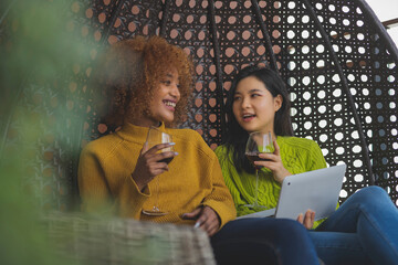 Two woman gossiping in the swing. Lesbian couple relaxing and drinking red wine. Close up. High quality photo