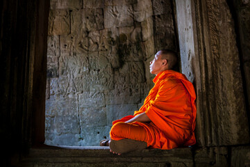 Novice monk in ruined building, Cambodia