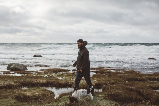 Man walking with dog along coast, Sweden