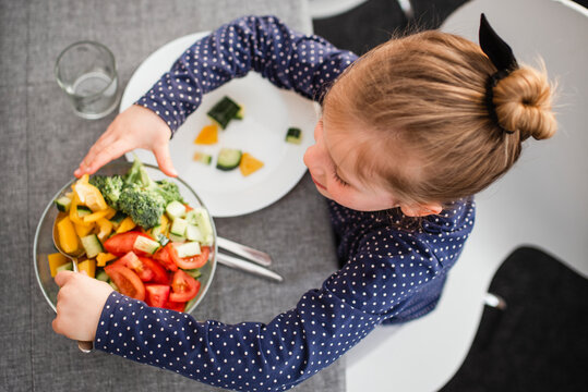 Girl putting salad on plate, Sweden
