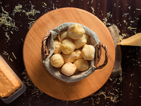 Cheese bread basket with slice of cheese, and grated cheese on rustic wooden table. Top View