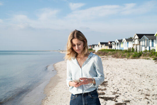 Woman on beach using phone, Sweden