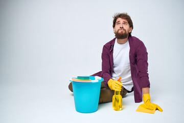 A man lies on the floor with a bucket of detergent cleaning service light background