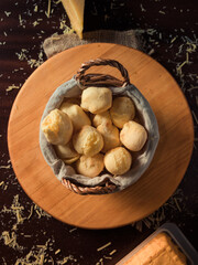 Cheese bread basket with slice of cheese, and grated cheese on rustic wooden table. Top View