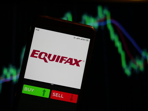 Company logo Equifax on smartphone screen, hand of trader holding mobile phone showing BUY or SELL on background of stock chart. Russia, Stavropol - May 29, 2019
