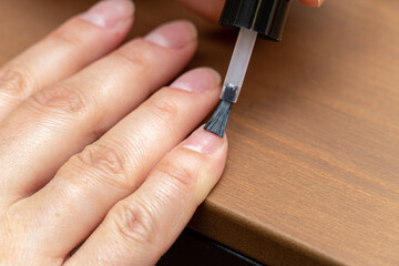 Applying primer, colorless nail polish with brush on finger