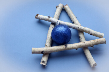 Christmas card: Christmas tree made of birch branches with a Christmas blue ball on a blue background, top view, place for the inscription