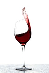 Close up view of splashing red wine in glass isolated on white background. 