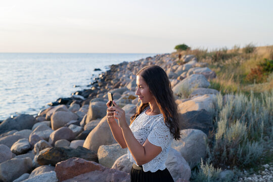 Woman taking photo at sea, Sweden