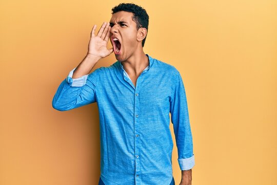 Young arab man wearing casual clothes shouting and screaming loud to side with hand on mouth. communication concept.