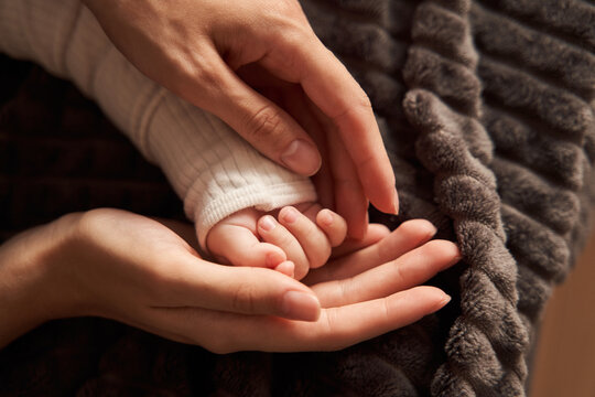 Mother holding hands of her little newborn