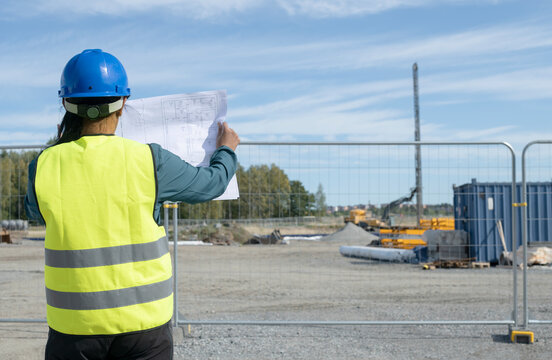 Woman holding blueprint at construction site, Sweden