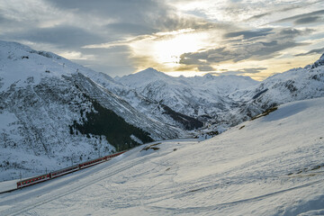 Train descending from mountain pass down to city of Andermatt in Switzerland