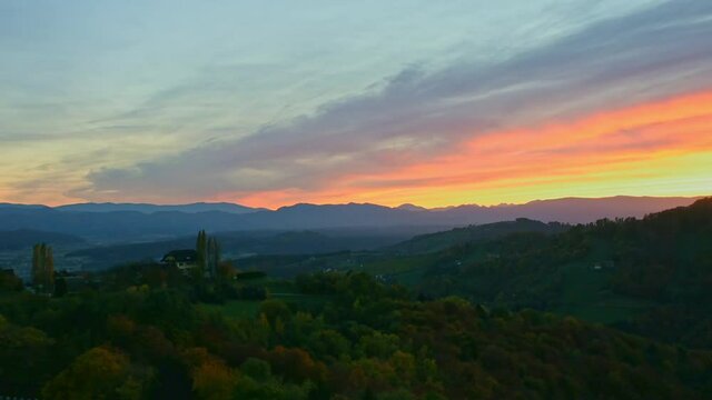 Autumn landscape with hills, Alps mountains and colorful trees in South Styria, a charming region on the border between Austria and Slovenia, at sunset.