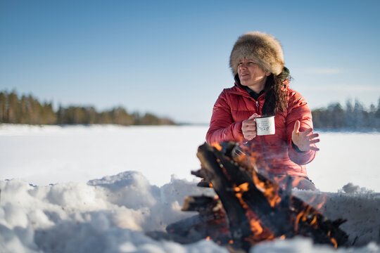 Woman holding mug near campfire, Sweden
