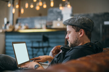 A man with a laptop works on the couch.