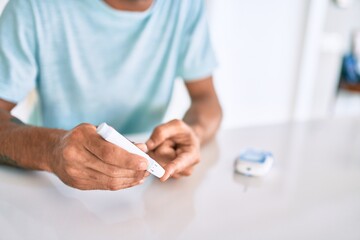 Young hispanic diabetic man measuring glucose level at home
