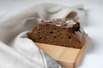 Cut black rye bread on a wooden board on a light background
