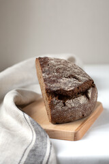 Cut black rye bread on a wooden board on a light background
