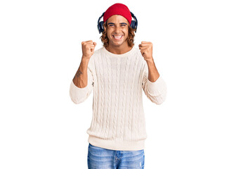 Young hispanic man listening to music using headphones celebrating surprised and amazed for success with arms raised and open eyes. winner concept.