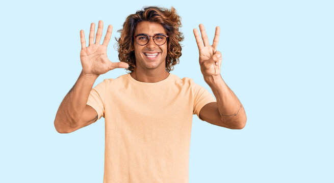 Young hispanic man wearing casual clothes and glasses showing and pointing up with fingers number eight while smiling confident and happy.