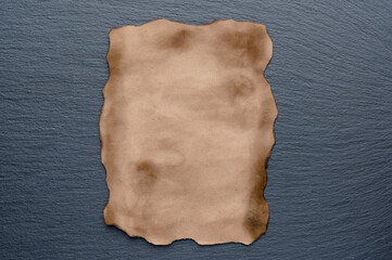 Burnt parchment sheet on gray stone background. Copy space. Restaurant menu concept.