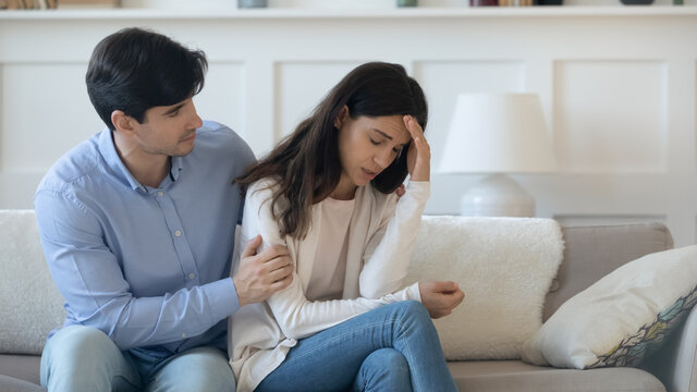 Comforting And Reassuring. Caring Young Man Husband Tender Hugging Shoulders Of Suffering Crying Woman Wife Encouraging Supporting In Grief Disaster Sharing Feelings Proposing Compromise After Quarrel