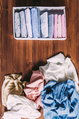 Perfectly folded clothes into home storage boxes, organizing space, scattered messy clothes