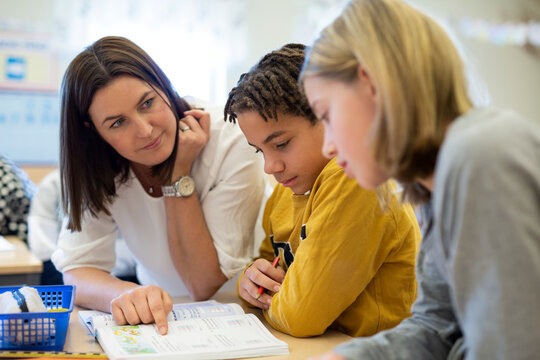 Teacher helping children in classroom, Sweden