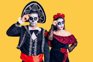 Young couple wearing mexican day of the dead costume over background worried and stressed about a problem with hand on forehead, nervous and anxious for crisis