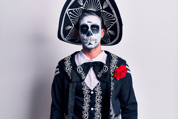 Young man wearing mexican day of the dead costume over white relaxed with serious expression on face. simple and natural looking at the camera.