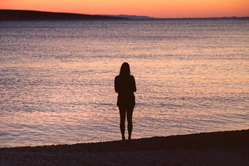 Silhouette of a girl on the seashore at sunset
