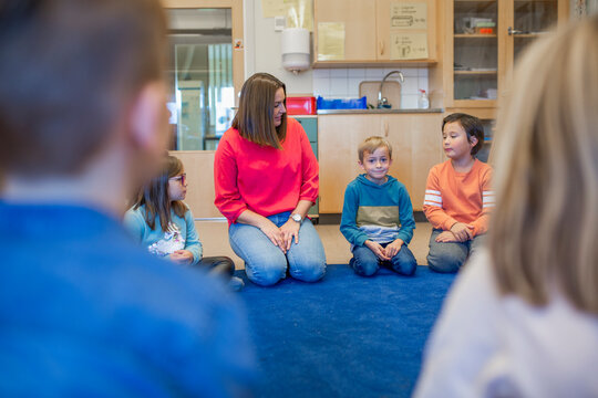 Teacher sitting on floor with children, Sweden
