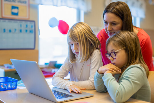 Teacher helping girls in classroom, Sweden