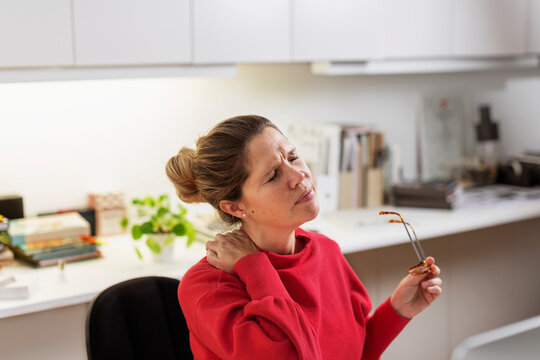 Woman massaging her neck at desk, Sweden