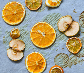 Fototapeta na wymiar dried slices of orange and lemon as well as apples on parchment, decoration for the new year, fruit chips.