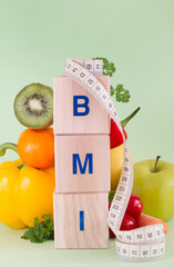  Word BMI made with wooden blocks. Fruits, vegetables and measuring tape, healthy diet concept