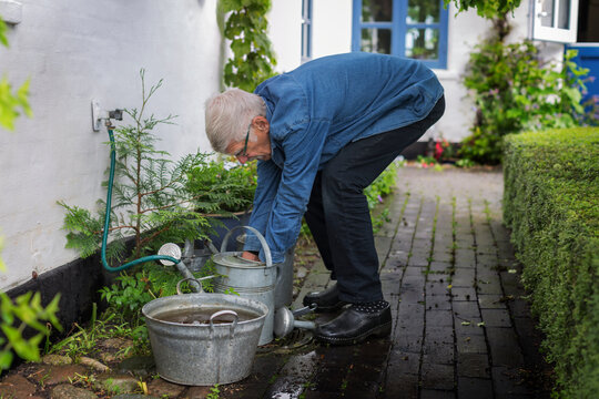 Man filling watering can, Denmark