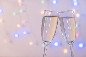 Champagne glasses pressed against each other from behind garland
