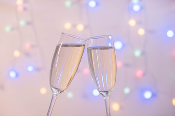 two full glasses of champagne pressed against each other from the back of a garland