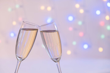 full glasses of champagne pressed together from behind garland