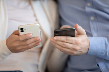 Communication of new generation. Close up of modern smartphones in millennial male and female hands at moment of sharing data using wireless internet technology, exchanging content in social networks