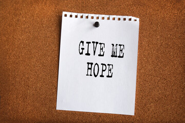Paper note written with GIVE ME HOPE inscription on cork board