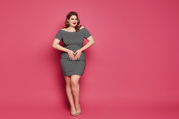 Plus-size model girl with bright makeup and with stylish hairstyle in a short dress isolated at the...