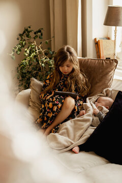 Girl with baby sibling on sofa, Sweden