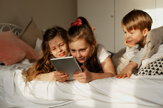 Children on bed using digital tablet, Sweden