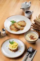 Restaurant set meal: potato fritters, mushroom cream soup and salad on a wooden table