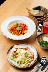 Business lunch in a italian cafe: caesar salad, chicken soup and tomato penne pasta, menu photography